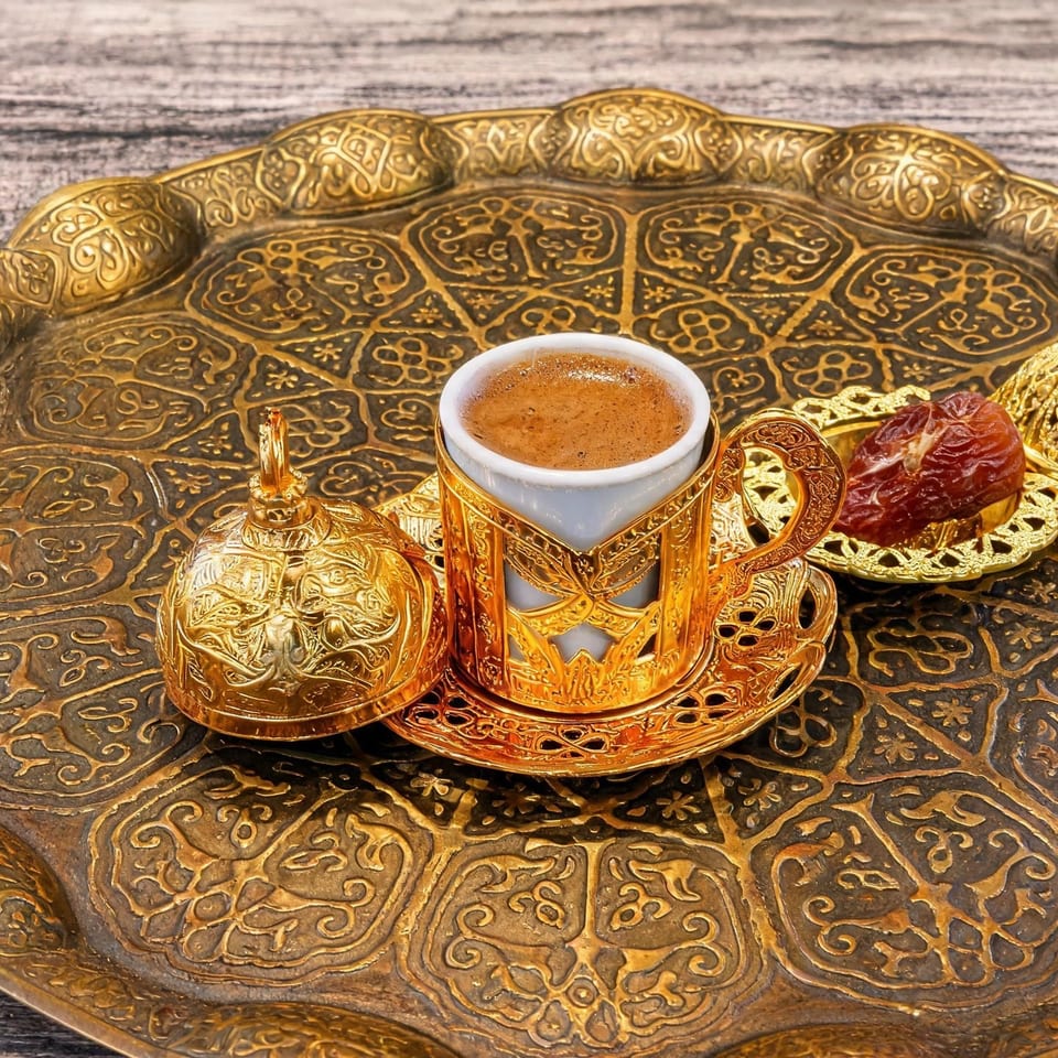 Turkish coffee served with a date on an ornate gold tray beside a decorative coffee pot and sugar bowl.