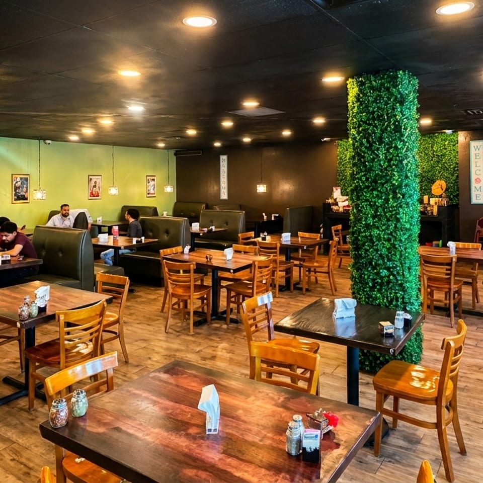 A restaurant interior with wooden tables and chairs, green booth seating, and customers dining.